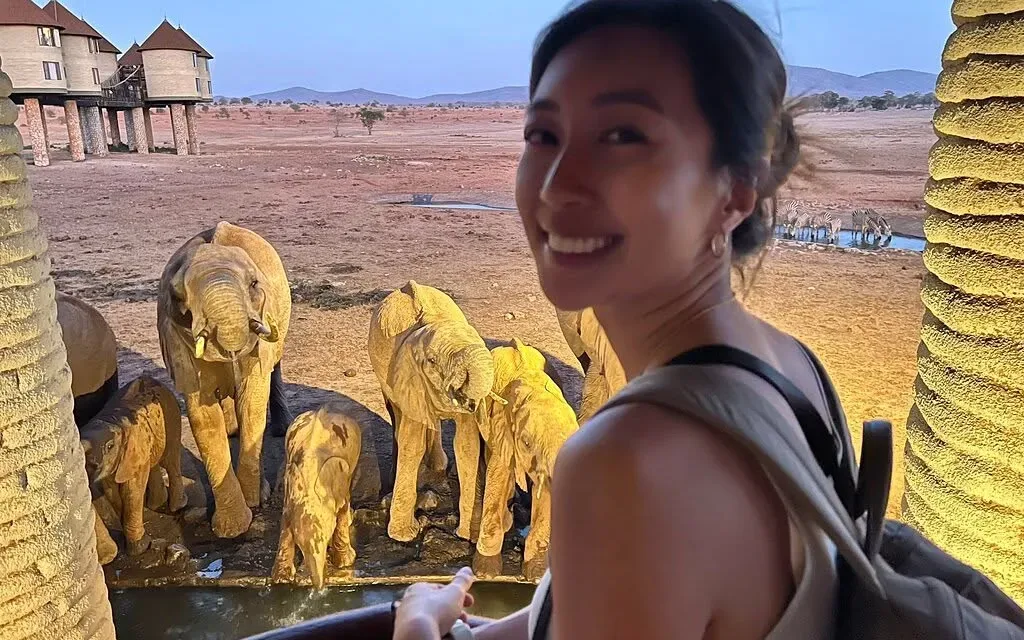 Guest watching floodlit elephants at a waterhole below a lodge in Tsavo