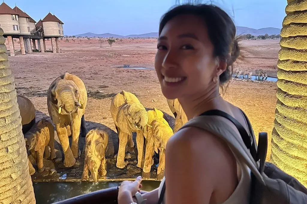 Guest watching floodlit elephants at a waterhole below a lodge in Tsavo