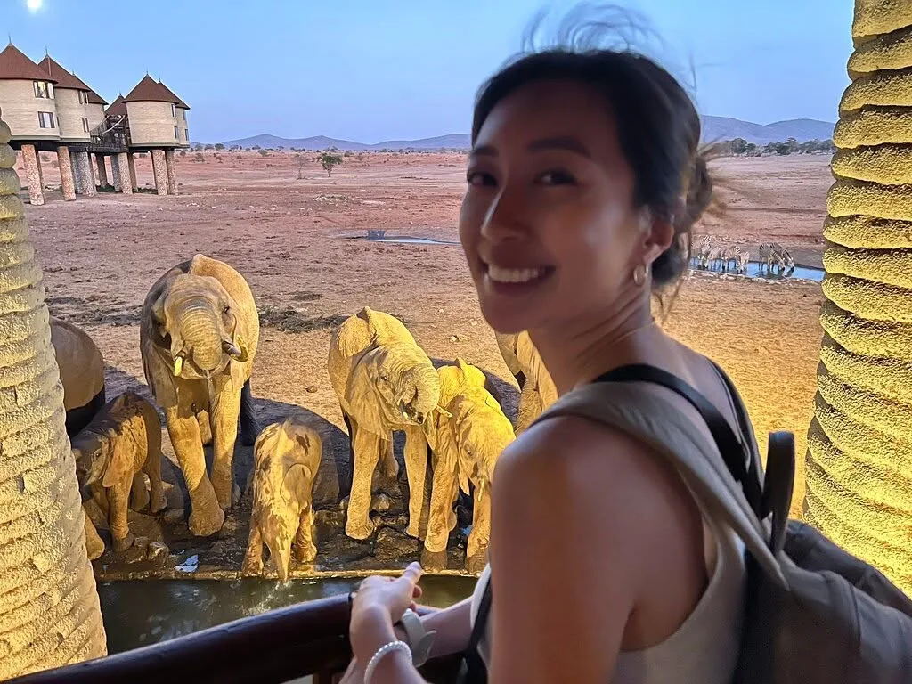 Guest watching floodlit elephants drinking at a waterhole below a lodge in Tsavo