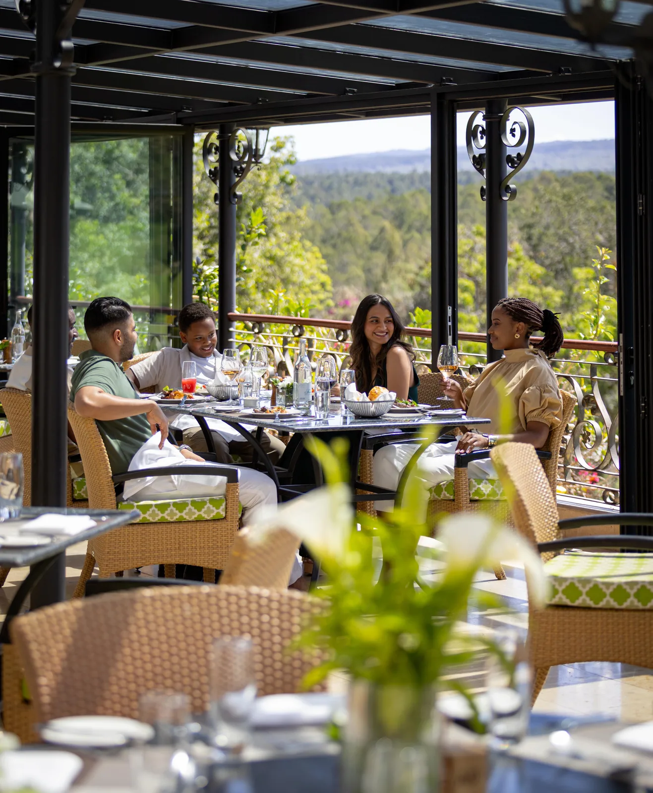 Guests dining on a lodge terrace with a view over forested hills