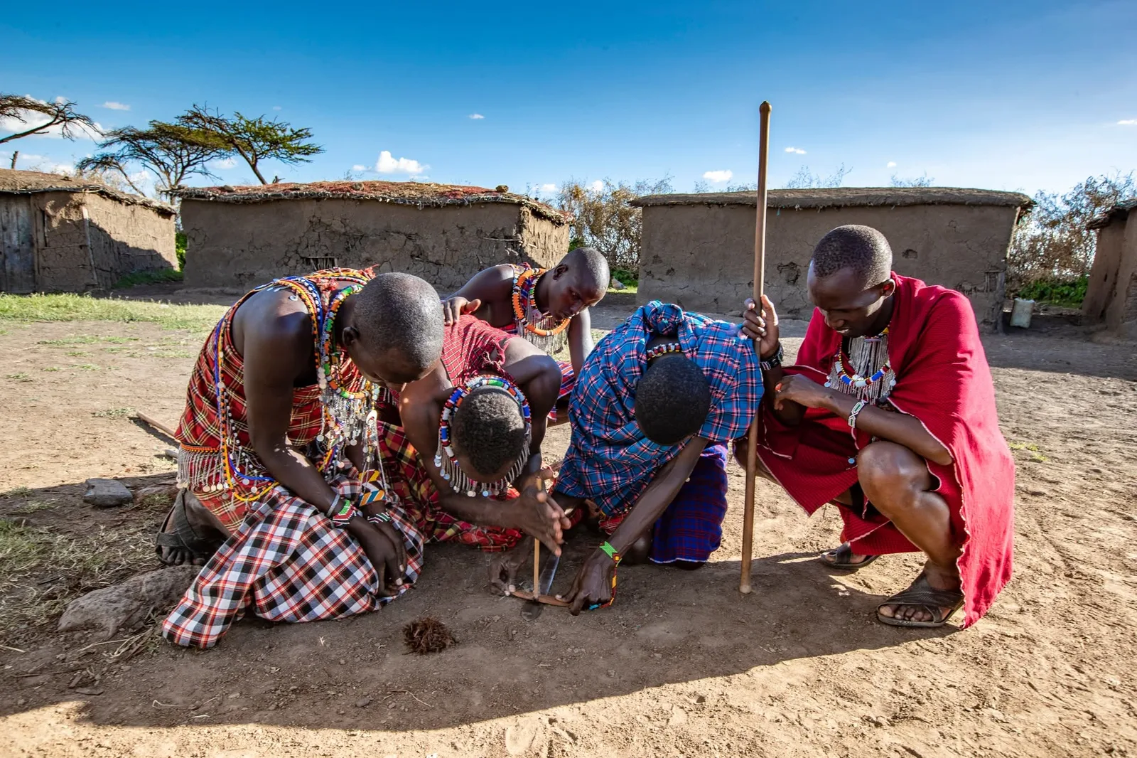 Maasai men demonstrating traditional fire making in a village near the Maasai Mara