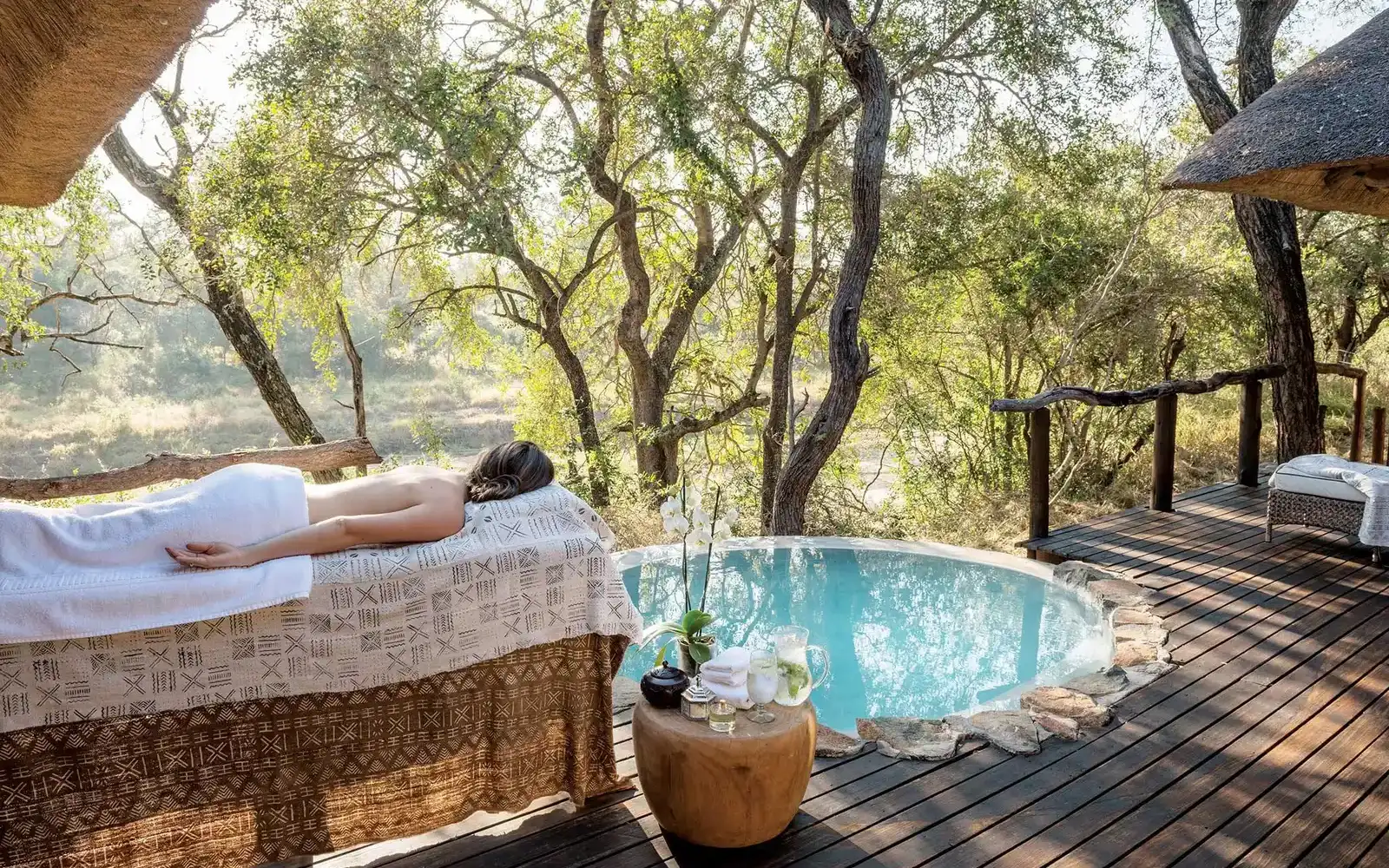 Spa bed and plunge pool on a wooden deck surrounded by trees