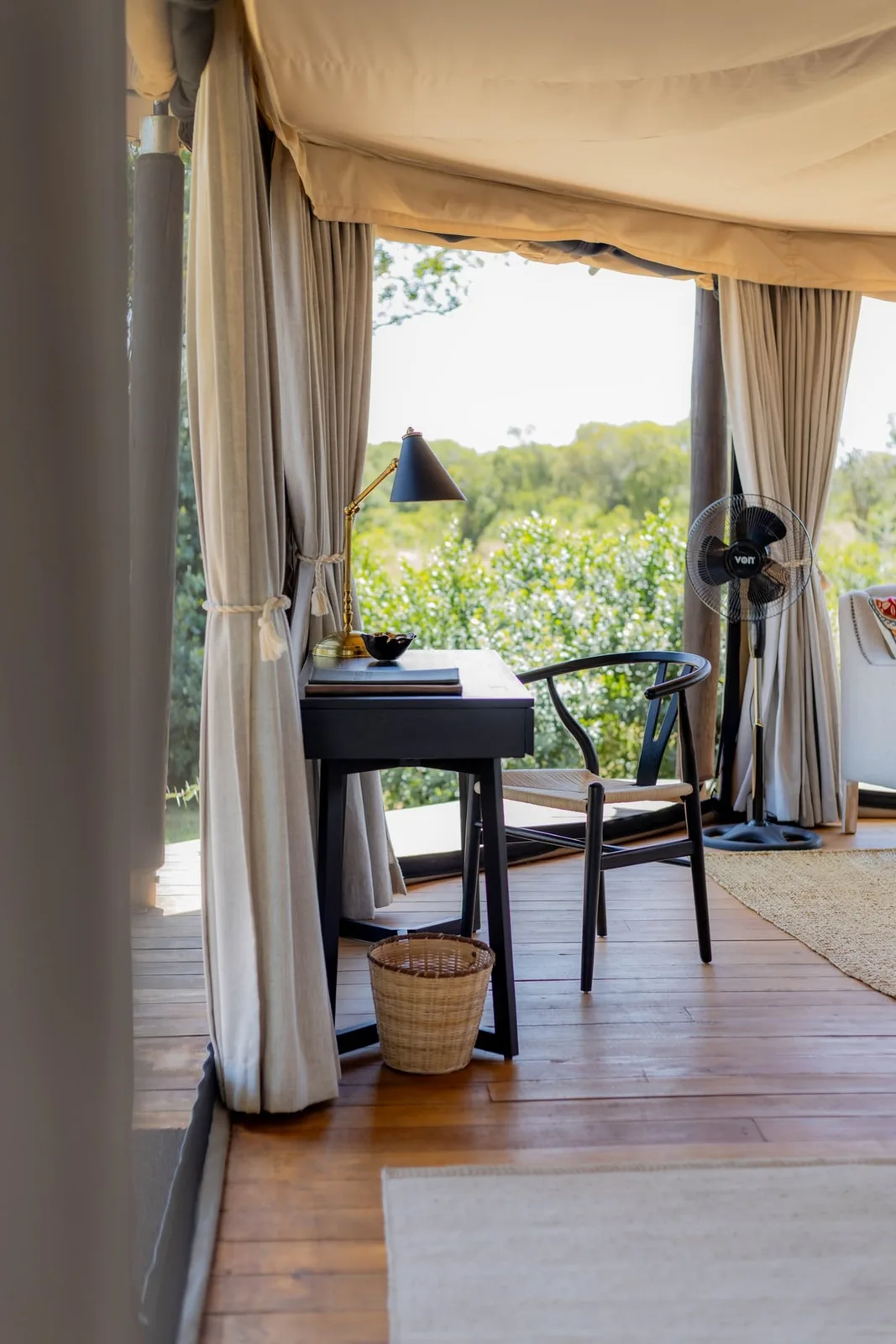 Writing desk and chair inside a canvas tented room looking out to green bush